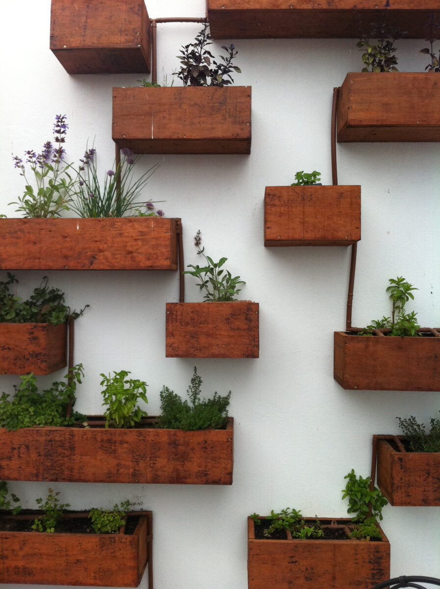 Hanging herb garden made of flowerpots and wooden planks.